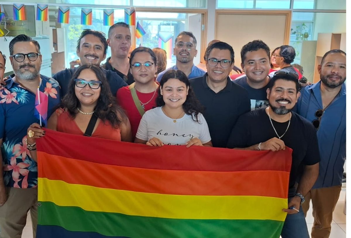 PERSONAS SOSTENIENDO UNA BANDERA LGBTIQ+